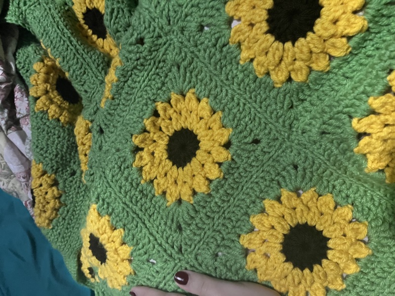 A crocheted sunflower granny square blanket in green and yellow